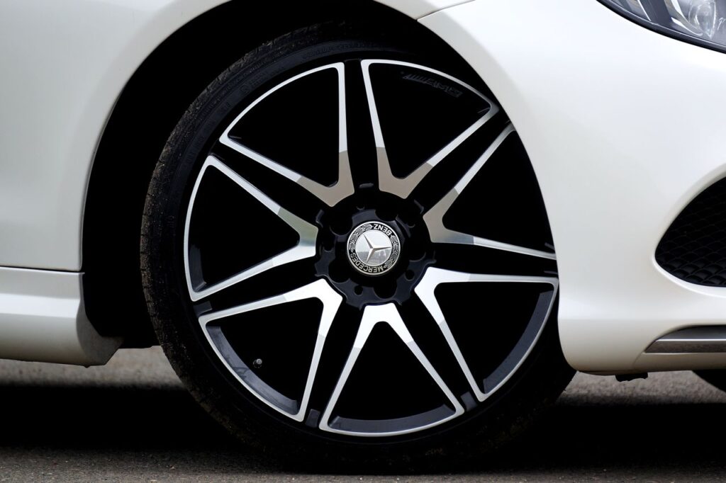 Close-up side view of a black and silver Mercedes-Benz AMG split-spoke alloy wheel on a white car.