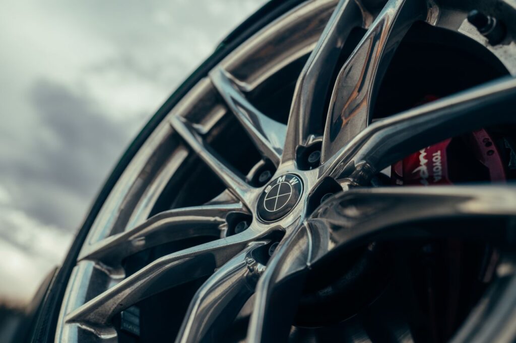 Low-angle close-up of a chrome multi-spoke BMW wheel with a red brake caliper visible behind it.