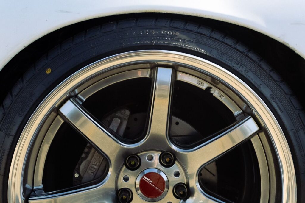 Close-up of a chrome Work Emotion six-spoke alloy wheel showing a red center cap and Nissan brake caliper.