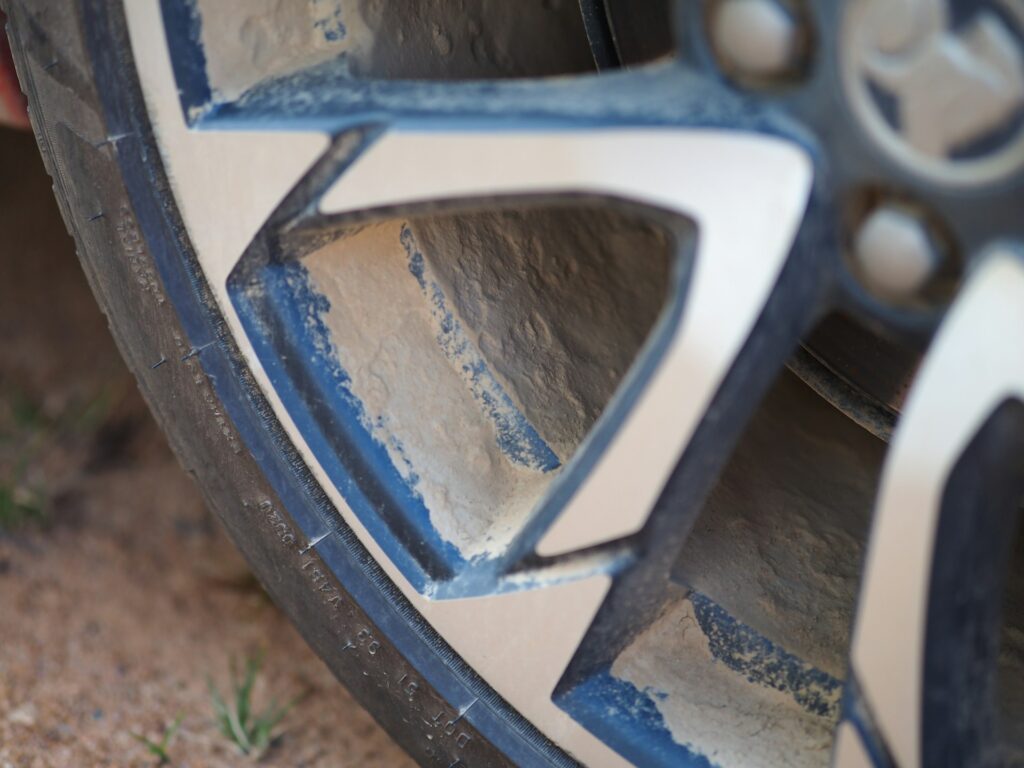 Extreme close-up of a dust-covered two-tone alloy car wheel and tire.