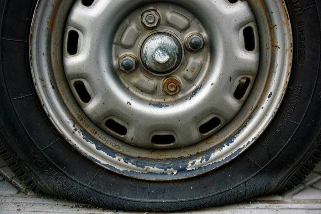 Close-up of a flat Yokohama tire mounted on an old, weathered silver steel wheel rim.