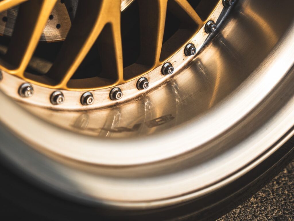 Detailed close-up of a gold mesh car wheel featuring a deep polished chrome lip and visible rim assembly bolts.