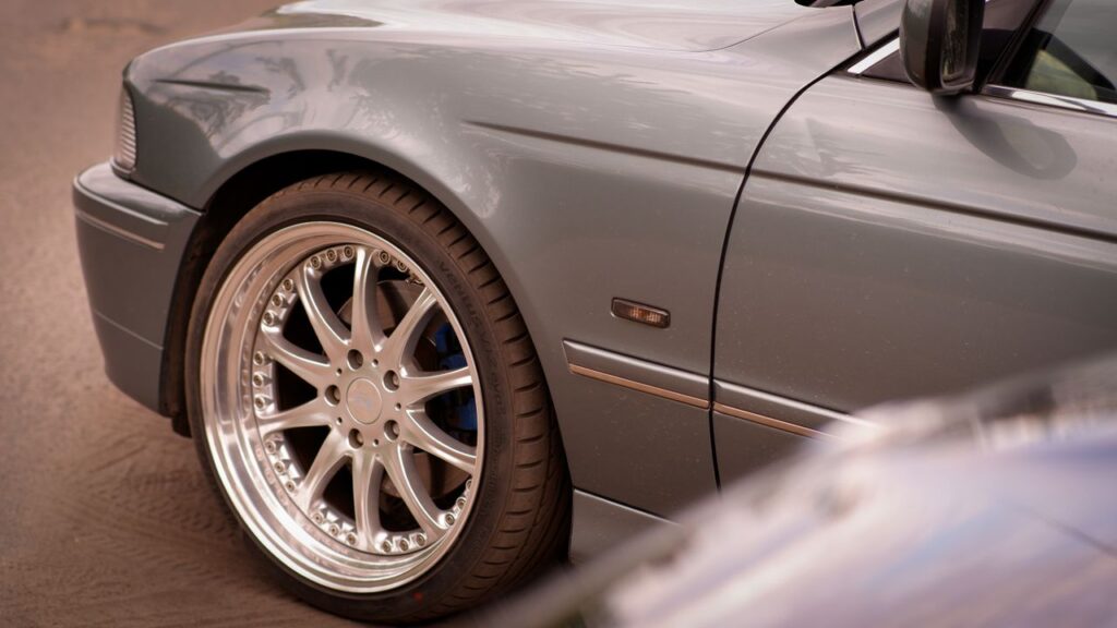 Front quarter view of a grey BMW featuring a silver deep-dish multi-spoke wheel with a polished lip.