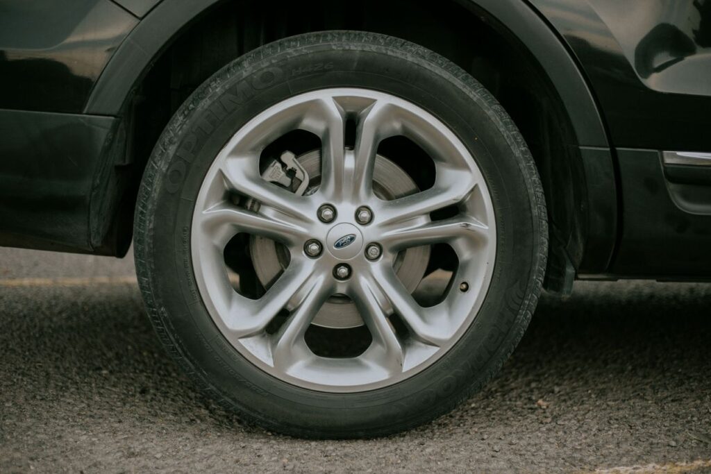 Close-up of a silver five-spoke Ford alloy wheel on a Hankook tire mounted on a dark vehicle.