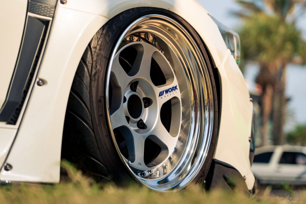 Low-angle close-up of a silver Work Wheels deep-dish rim mounted on a slammed white car.